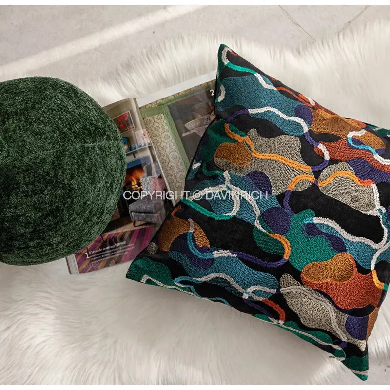 A vibrant multicolor geometric embroidery abstract cushion cover with teal orange purple and gold on black decorbites design