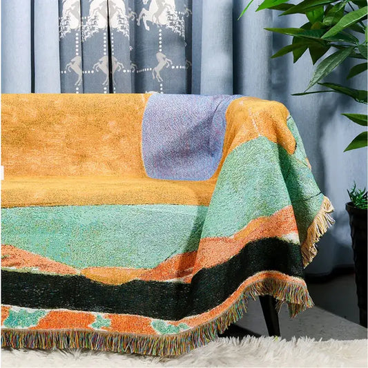A cozy multicolor patchwork jacquard tapestry blanket with orange teal purple black stripes and fringed edges for living room use