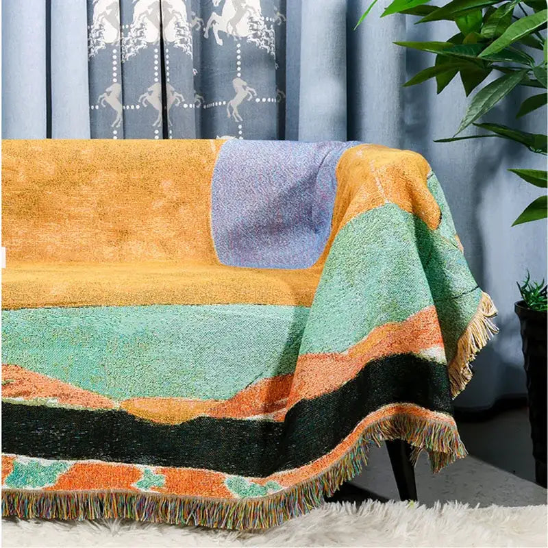 A cozy multicolor patchwork jacquard tapestry blanket with orange teal purple black stripes and fringed edges for living room use