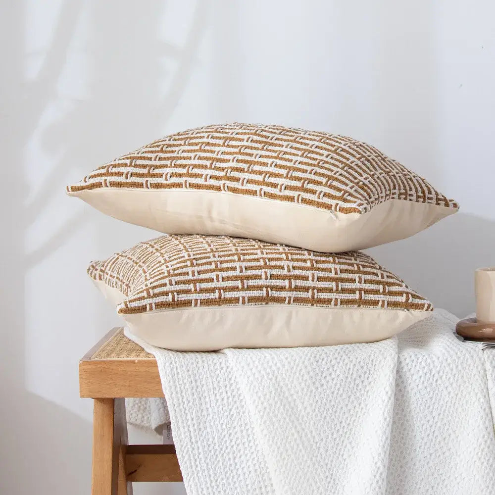 Two beige mustard and cream cotton woven texture cushion covers with geometric pattern stacked on wooden stool decorbites cotton woven