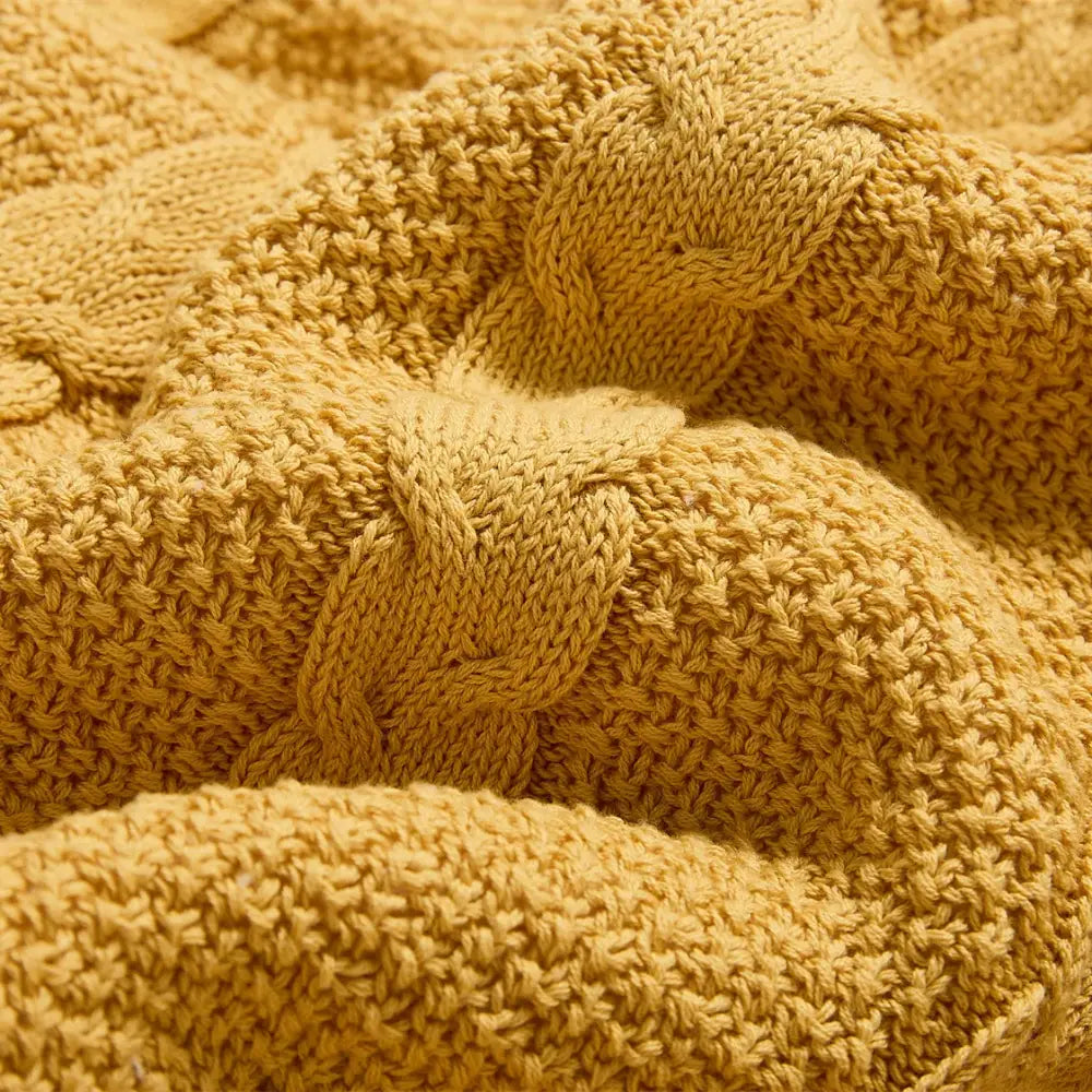 A cozy mustard-yellow cable knit sherpa blanket with chunky texture by decorbites perfect for bedroom decor