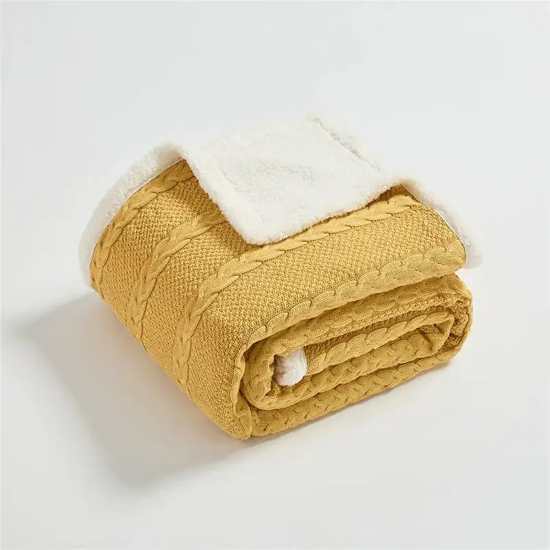 Cozy mustard yellow decorbites cable knit sherpa blanket with plush white fleece interior and decorative braided pattern