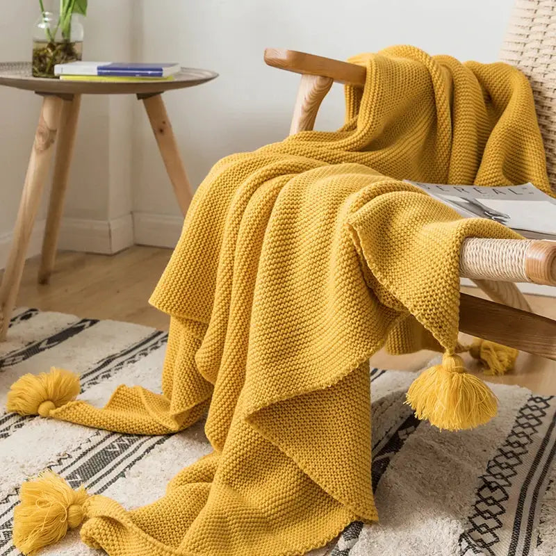 A cozy mustard yellow knit pompom tassel throw blanket with textured stitches and fluffy tassels for bedroom decorbites decor