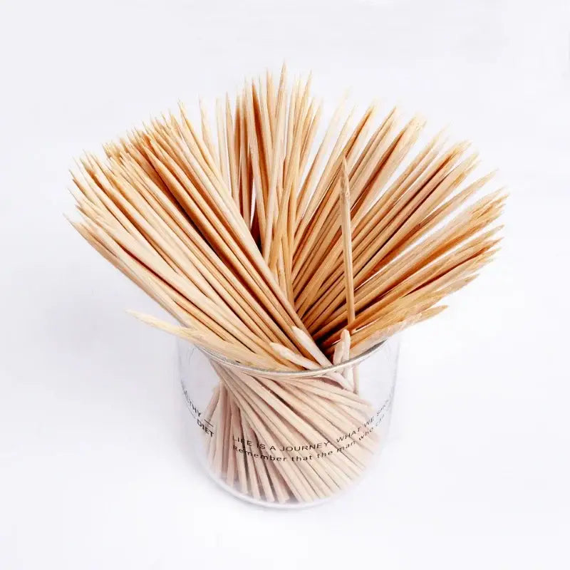 A clear glass container filled with light brown natural bamboo bbq skewers for kitchen grilling use