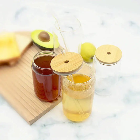 Clear glass cups with decorbites bamboo lids filled with amber and light yellow beverages for kitchen drinkware accessory