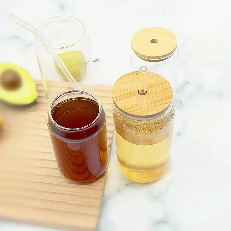 Clear glass cups with decorbites bamboo lids and built-in straws filled with amber and light yellow drinks