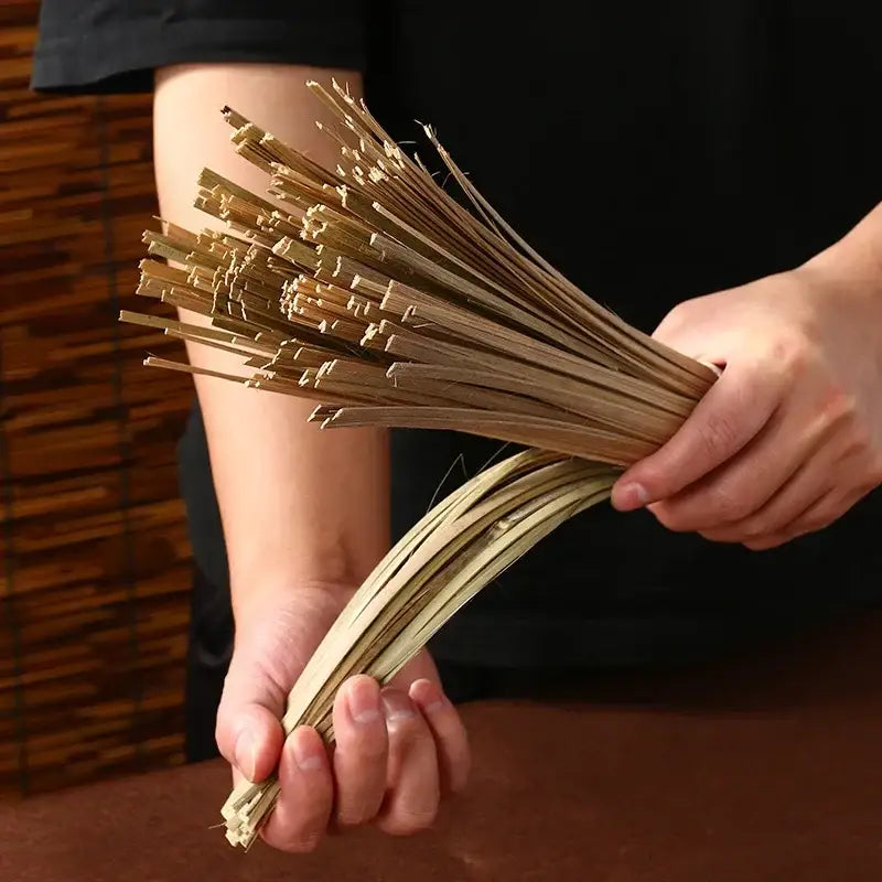 A bundle of light brown slender bamboo strips held in hands for a natural pot brush green cleaning decorbites bamboo kitchen set