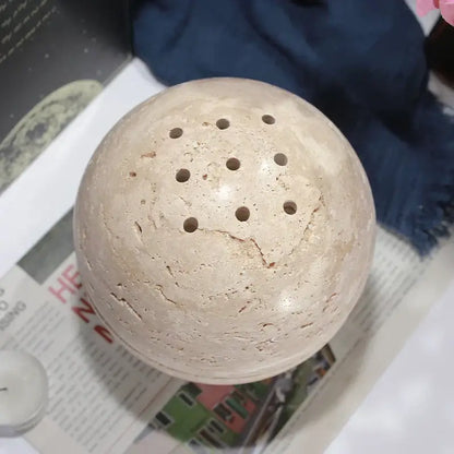 Beige travertine spherical incense burner with evenly spaced circular perforations for living room decor by decorbites