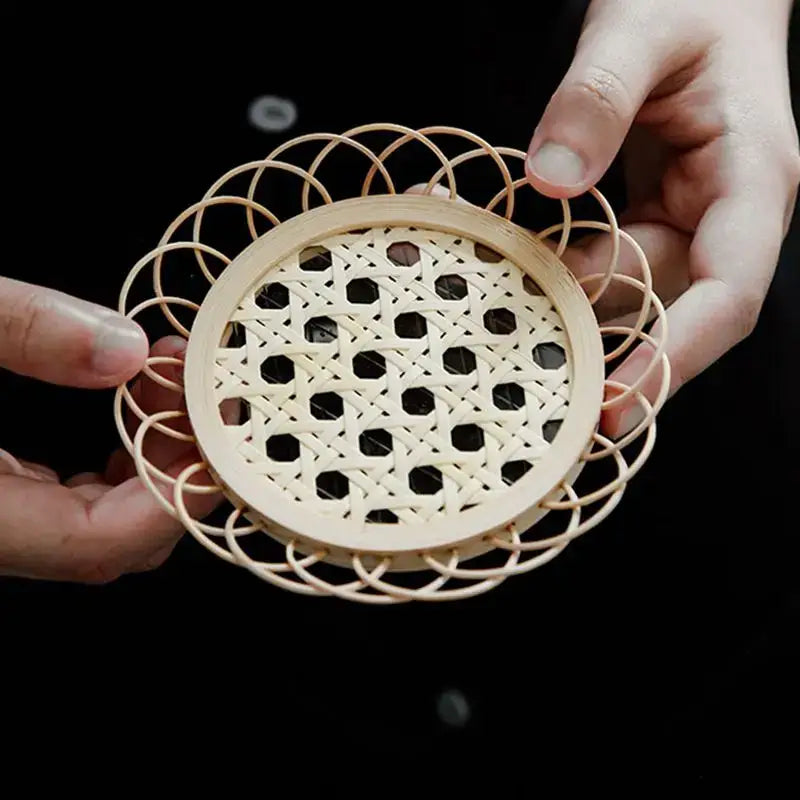 A delicate light beige bamboo woven coaster with an intricate pattern from a storage basket set for dining room use