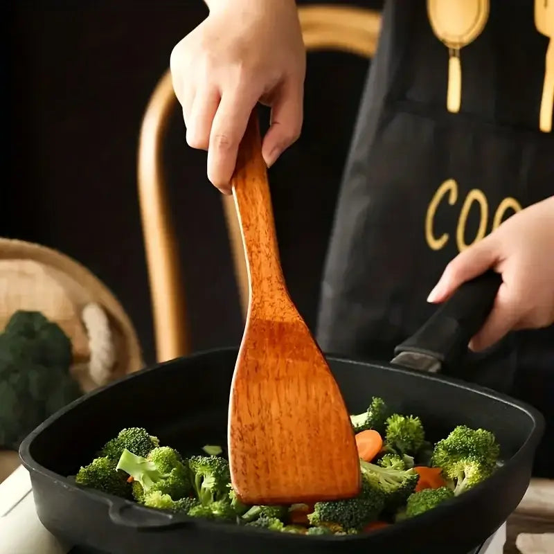 Natural polished warm-toned wooden kitchen utensil set featuring a smooth wooden spatula with visible wood grain