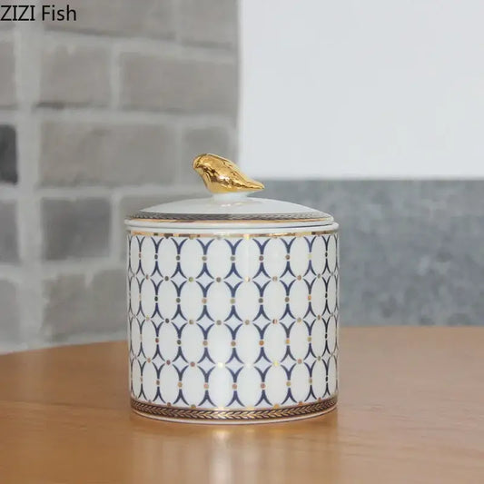 White ceramic navy and white geometric storage jar with gold plated trim and decorbites gold plated bird figurine topper