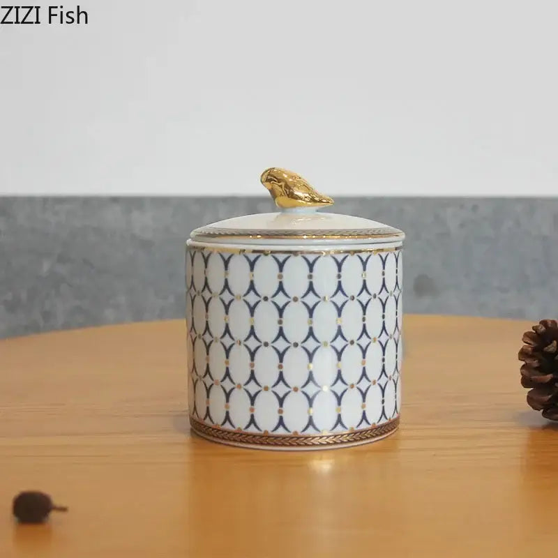 White ceramic storage jar with navy blue geometric pattern and gold plated bird figurine decorbites gold plated design