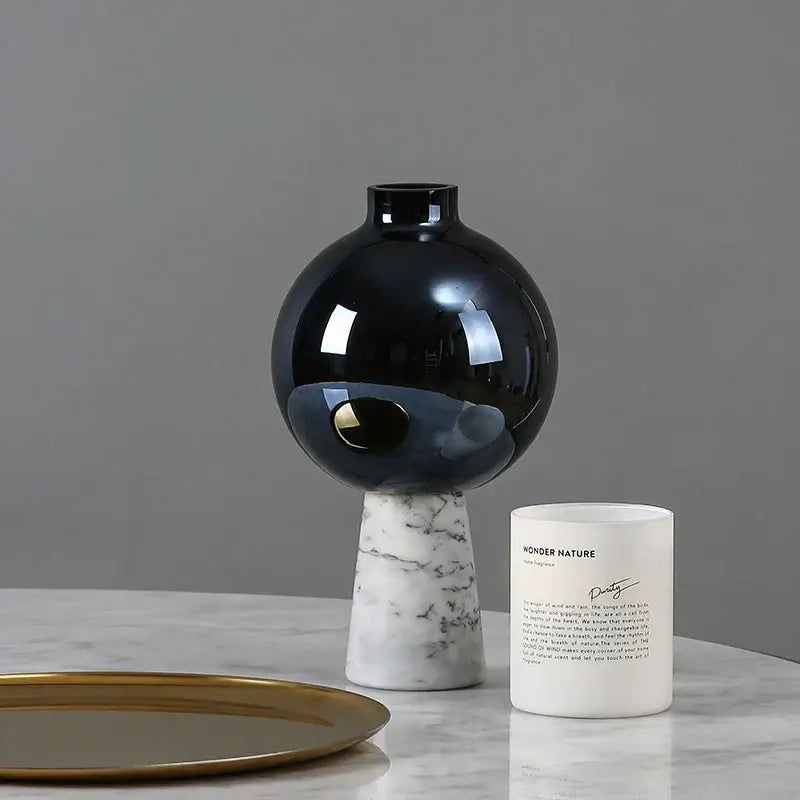 Glossy black ceramic vase with gold geometric circle star detail on white marble base for living room decor