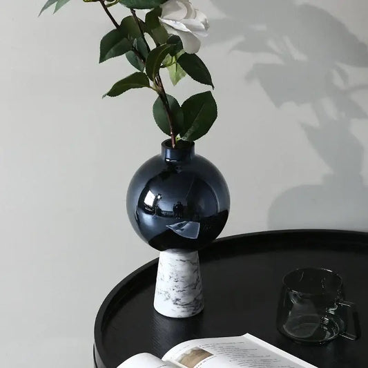 A sleek glossy navy blue geometric circle star glass vase with marble-patterned base holds a single white flower