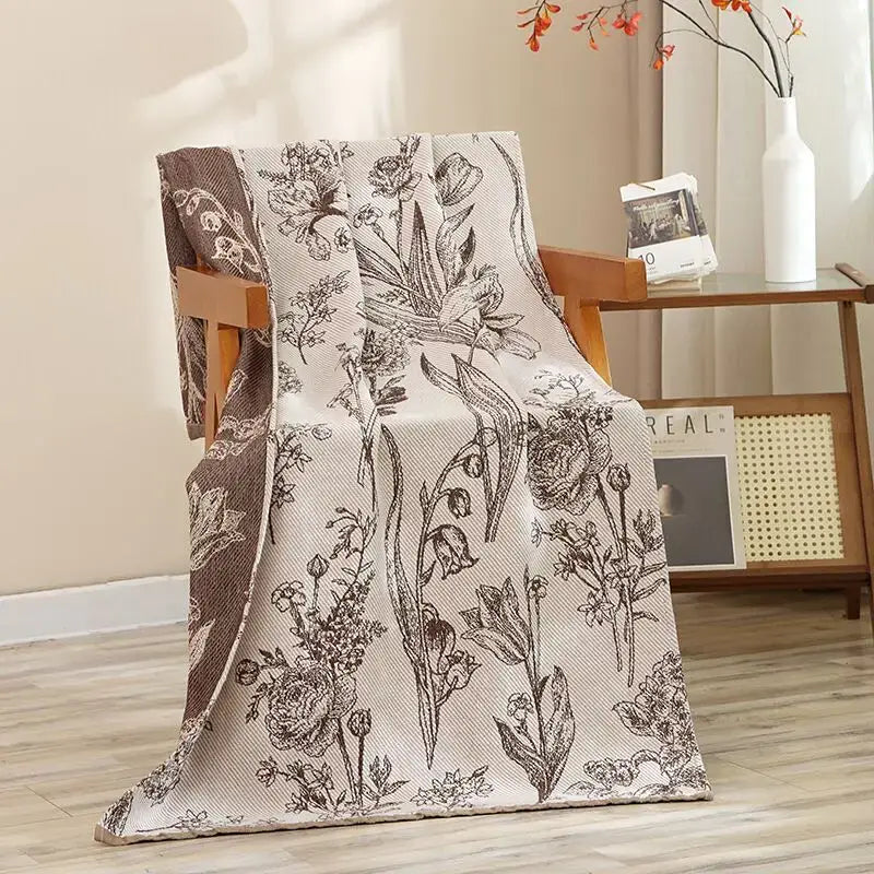 Beige cotton gauze throw blanket with black floral embroidery and brown border draped over chair for decorbites cat bath towel decor