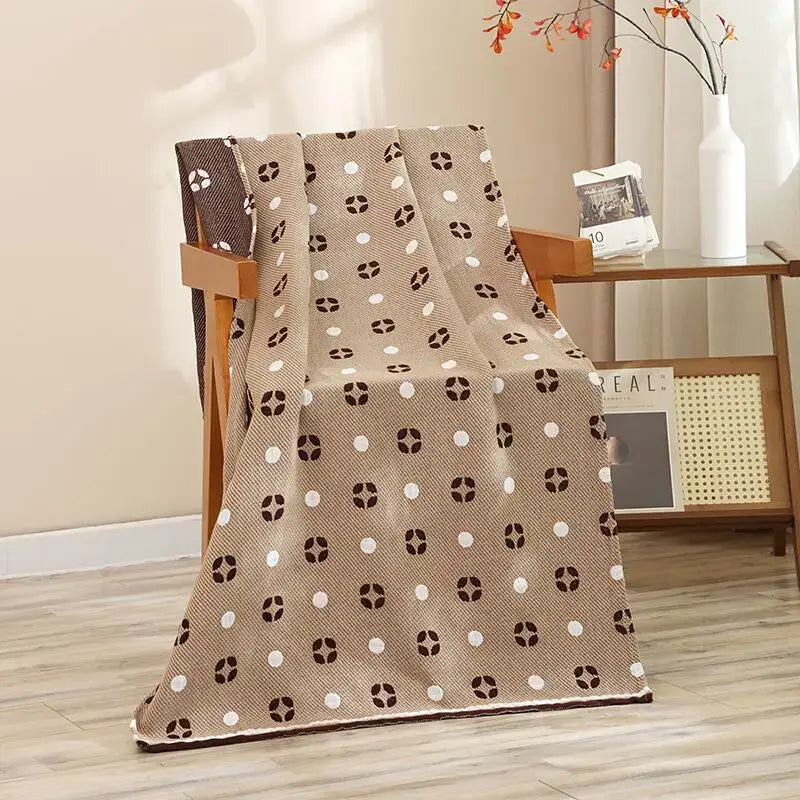 Beige cotton gauze throw blanket with white and dark brown circular motifs draped on chair complementing cat bath towel decorbites