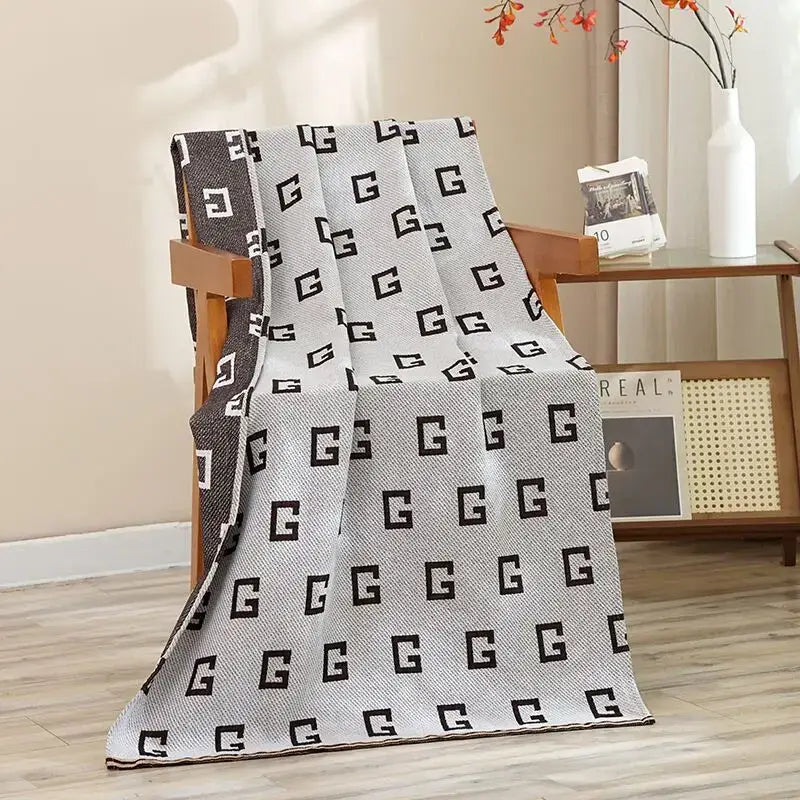 Navy blue gold hibiscus cat bath towel made of cotton gauze with a gray and black knitted geometric g patterned throw blanket