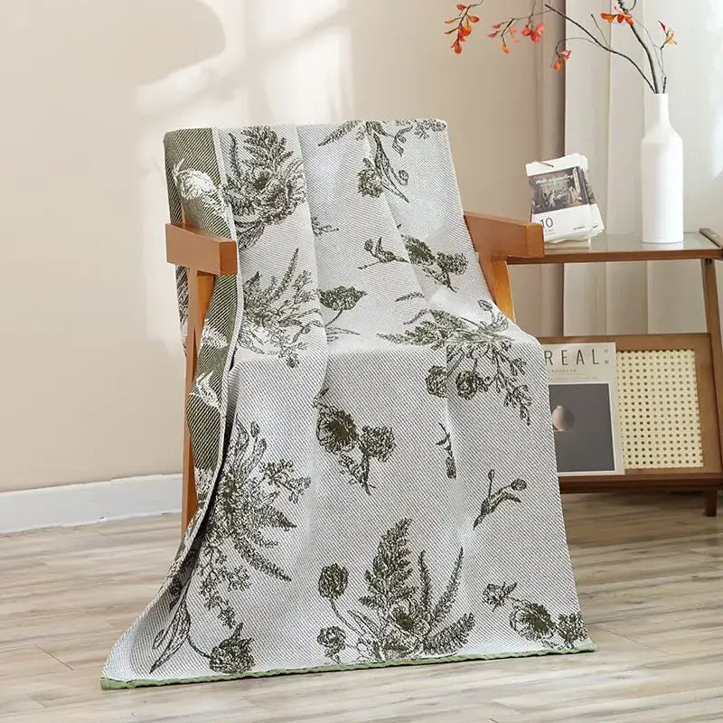 A light gray woven throw with dark green botanical pattern draped over a chair for decorbites cat bath towel use