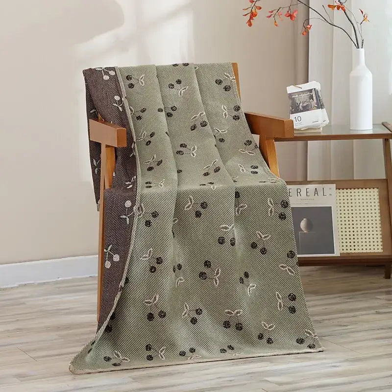 Olive green woven blanket with cherry pattern draped on wooden chair complements decorbites cat bath towel cotton gauze