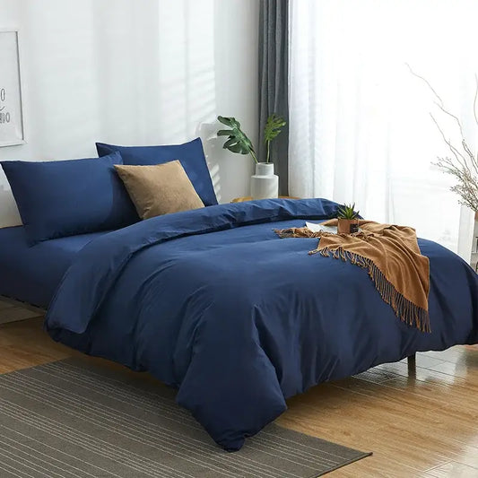 Deep navy blue solid color decorbites cotton 4pcs bedding set with matching pillows and tan throw blanket draped on bed