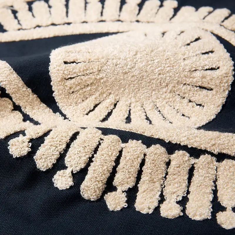 Beige textured skull and crossbones embroidered cotton patch on navy and cream pillow cover for living room decor