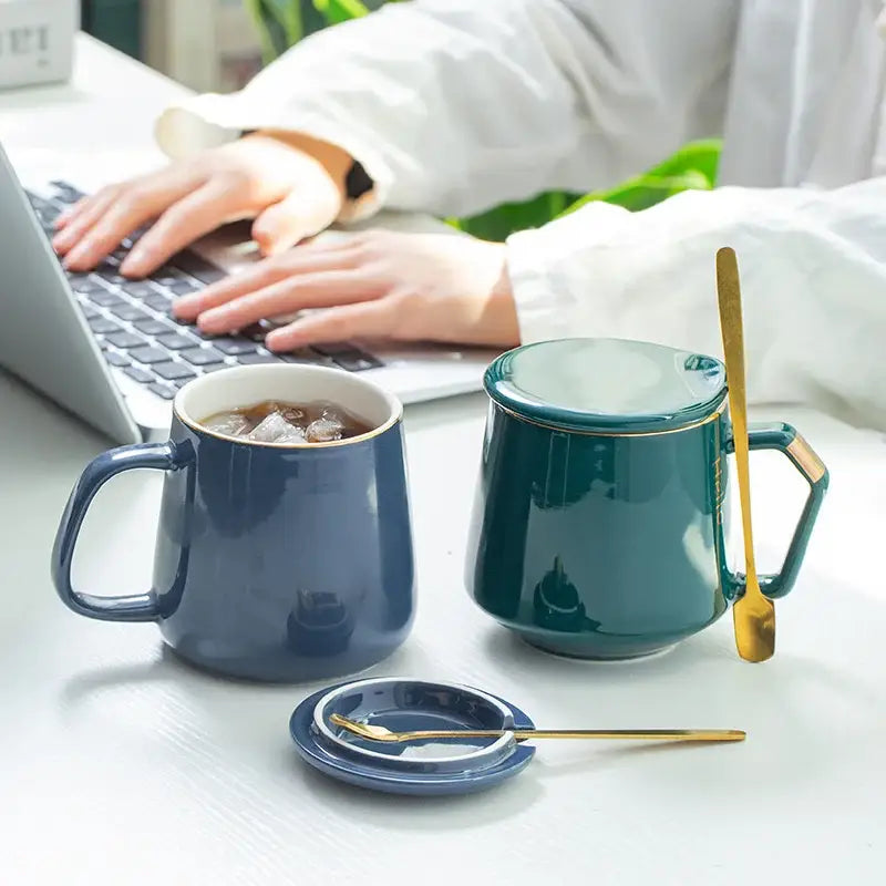 Deep teal ceramic mug set with gold-trimmed lid handle and matching spoon from navy and emerald ceramic mug set