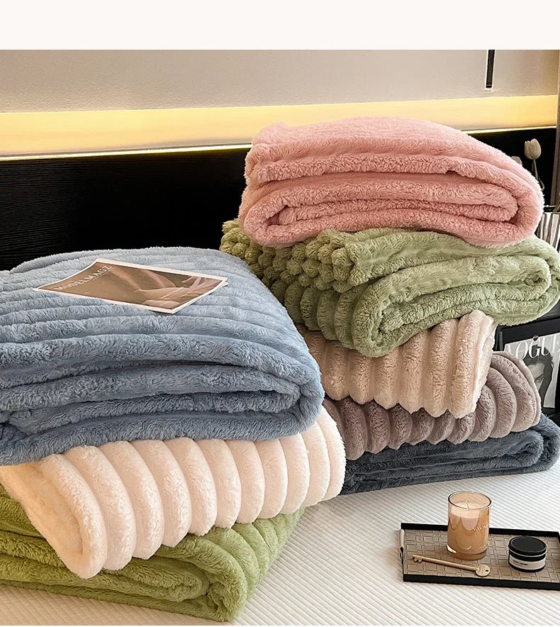 Stack of pastel throw blankets in pink blue green and beige soft coral fleece and bamboo fiber for autumn warmth