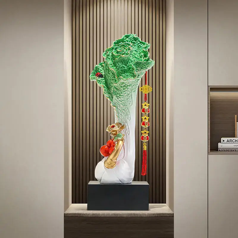 A glossy green and white ceramic decorbites cabbage ornament with golden accents and red tassels for office decor