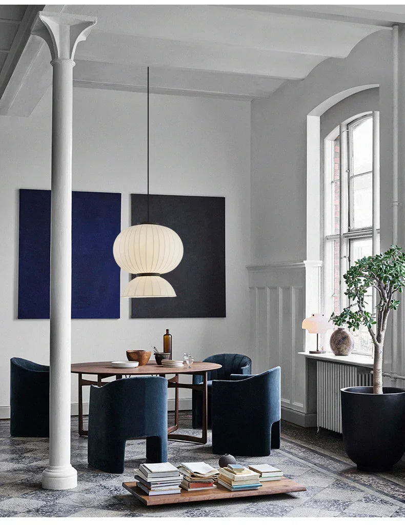A modern noguchi pendant light with a soft white fabric shade hangs as a dining room shop hanging lantern light