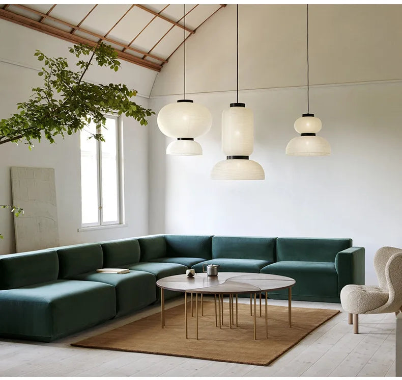Emerald green velvet sectional sofa with modern lines beside a noguchi rice paper lantern light for dining room decor