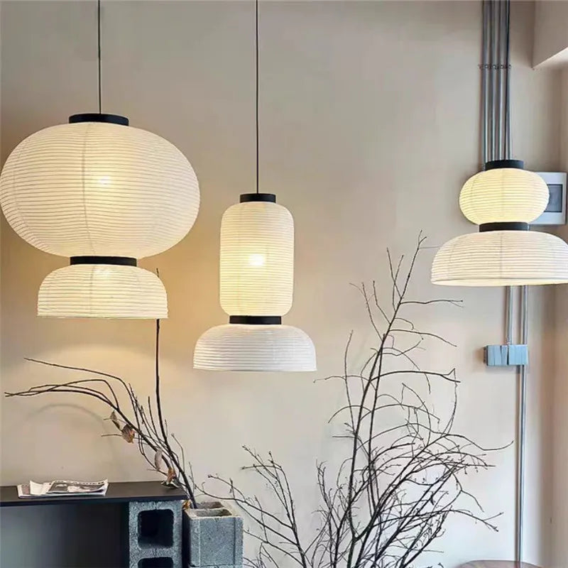 Three elegant white rice paper lantern lights with black metal accents hang as a shop hanging light for dining room decor