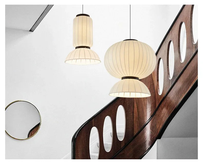 Cream-colored ribbed fabric noguchi pendant light with dark metal accents hanging above wooden staircase for dining room decor shop hanging light