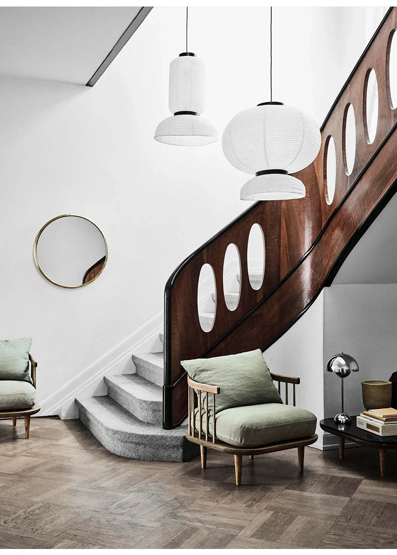 A minimalist wooden staircase with dark brown finish and oval cutouts near a dining room rice paper lantern light