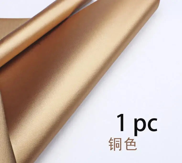 A roll of copper-colored metallic fabric with a smooth satin finish for a non-stick black bbq grill mat accessory
