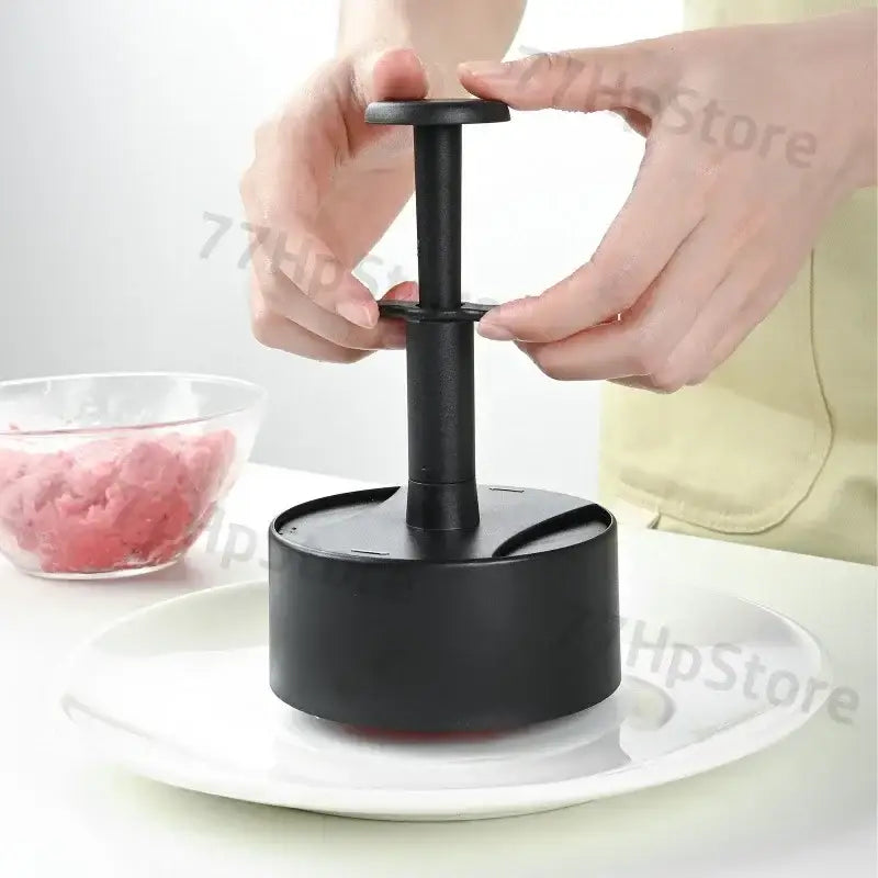 Black plastic hamburger meat press with cylindrical handle and circular base for non-stick meat patty molding