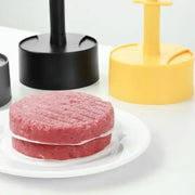 Two round pinkish-red ground beef patties with grill marks on a white plate made using a non-stick hamburger meat press