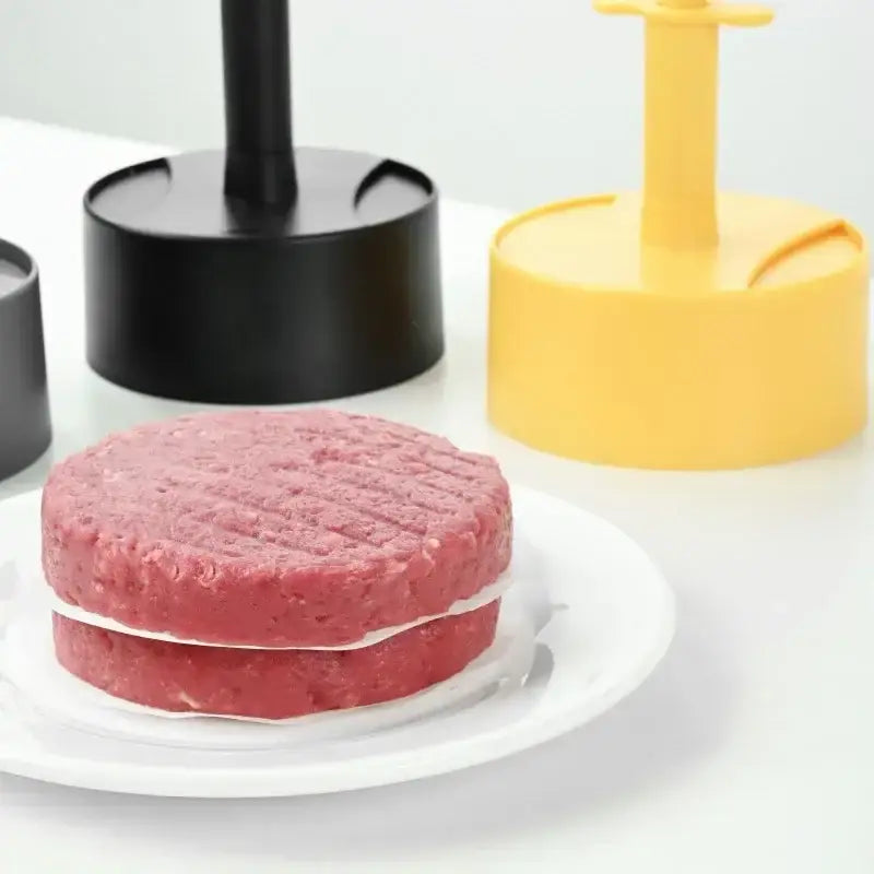 Two round pinkish-red ground beef patties with grill marks on a white plate made using a non-stick hamburger meat press