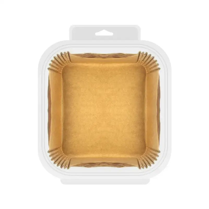 Square-shaped brown nonstick parchment paper liners with fluted edges packaged in a clear container for air fryer baking
