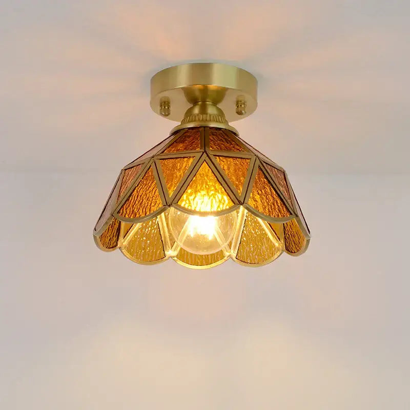 A warm amber-tinted glass copper led ceiling light with brass frame and geometric petal design for bedroom use