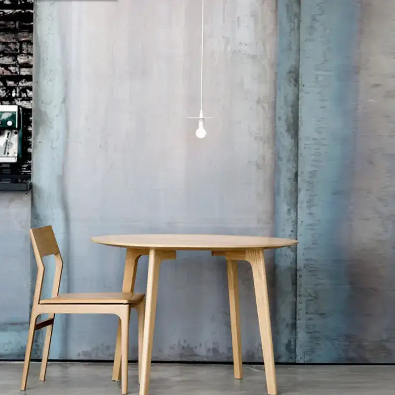 Minimalist round oak dining table with tapered legs and matching chair under nordic black iron pendant light decorbites iron pendant