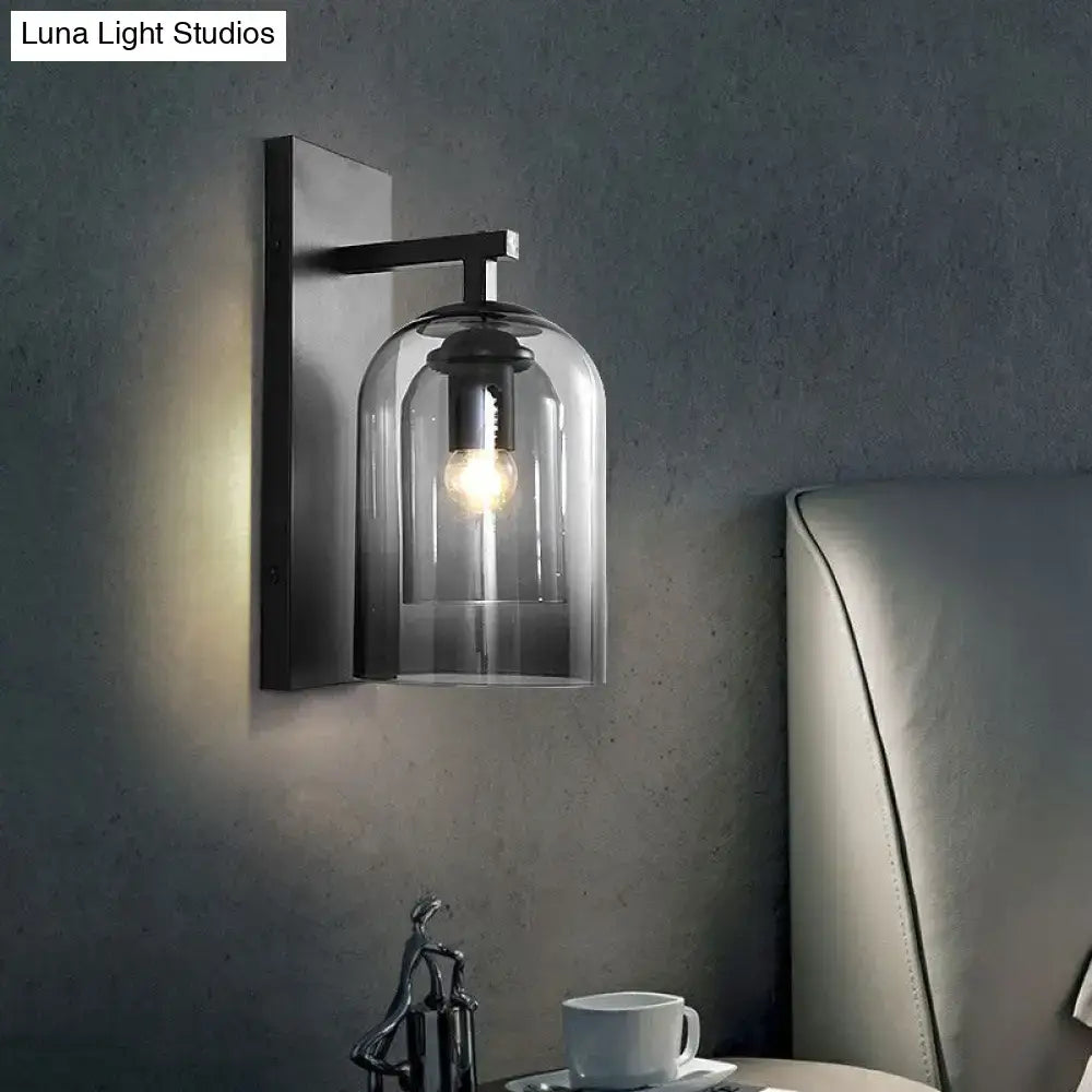 Black metal wall lamp with clear smoked glass dome and exposed bulb designed as a bedroom sconce