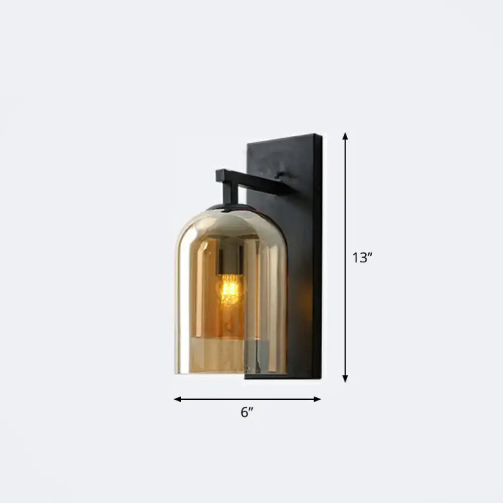 Black metal wall lamp with a warm amber smoked glass dome and exposed bulb for bedroom use