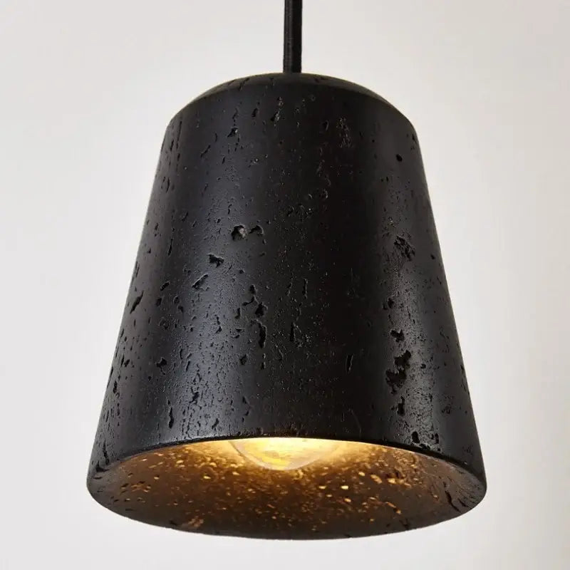 Black travertine pendant light with textured speckled surface and warm gold interior lining for dining room decorbites black travertine