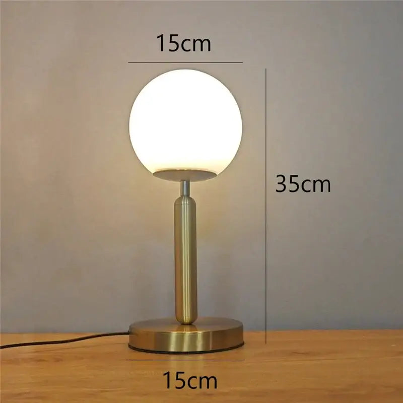 A sleek brass finish table lamp with a frosted glass ball led shade ideal for bedroom decorbites decorbites glass ball