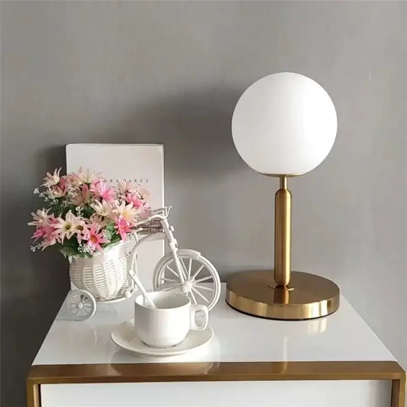 A modern nordic table lamp with a frosted glass ball led shade and polished brass base for bedroom decorbites decor