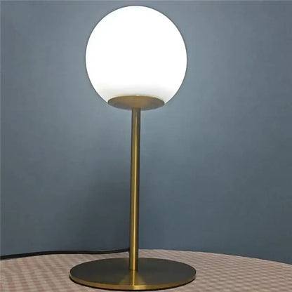 A sleek nordic brass finished table lamp with a frosted white glass ball led shade for bedroom decorbites decor