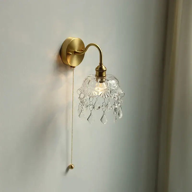Gold-toned nordic brass crystal glass led wall light with clear faceted shade and dangling crystal droplets decorbites crystal glass