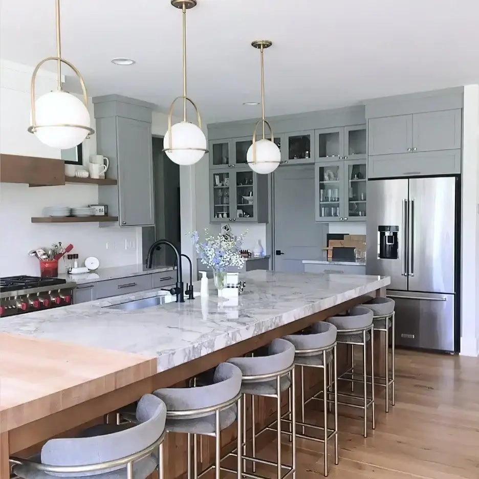 Nordic brass glass globe pendant light with white globe shades and brass frames hangs above marble kitchen island