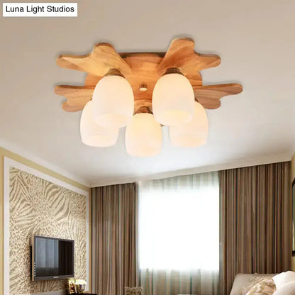 Wooden ceiling light with five cream glass bell shades and leaf-like wooden base for bedroom lighting