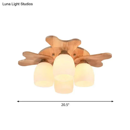 Wooden ceiling light fixture with three cream glass bell shades and leaf-shaped wooden arms for bedroom use